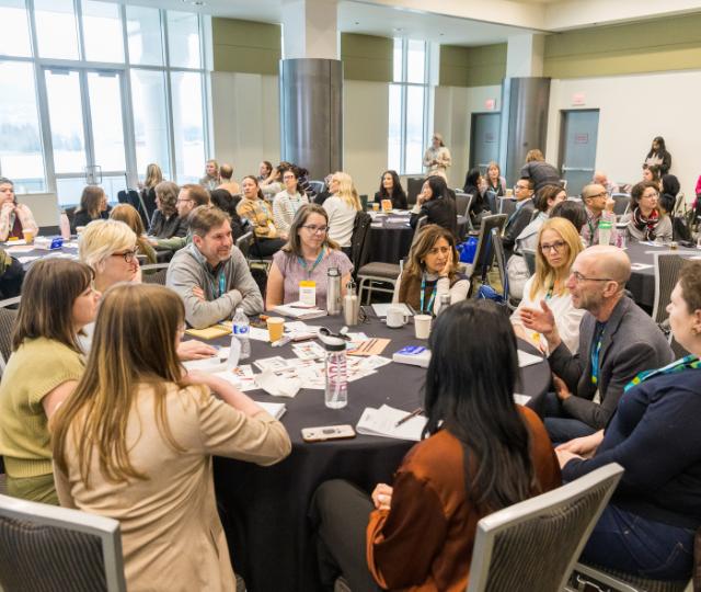 Conference attendees in animated discussion around a round table